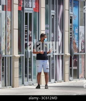 30. April 2020, Orlando, FL, USA: A Lone, der maskierte Fußgänger schaut am Donnerstagnachmittag in Richtung eines verlassenen International Drive. Die meisten Läden werden als Reaktion auf die Coronavirus-Pandemie zumindest vorübergehend geschlossen. (Kreditbild: © TNS via ZUMA Wire) Stockfoto