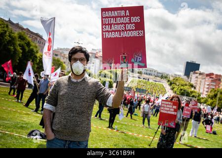 1. Mai 2020, Lissabon, Portugal: Ein Mann mit einer Gesichtsmaske hält während der Kundgebung zum Internationalen Arbeitstag ein Plakat. Hunderte versammelten sich in Lissabon, um den Arbeitstag (Alameda Dom Afonso Henriques) zu feiern, der von der CGTP-union organisiert wurde, während sie strenge soziale Distanzierungsregeln in einem kleineren als üblichen Ereignis behielten, um Solidarität mit denjenigen zu zeigen, die aufgrund des Coronavirus-Ausbruchs arbeitslos sind. (Kreditbild: © Henrique Casinhas/SOPA Images via ZUMA Wire) Stockfoto