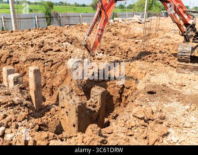 Ein Minibagger entfernt Schmutz aus der Nähe des Pfahls. Stockfoto