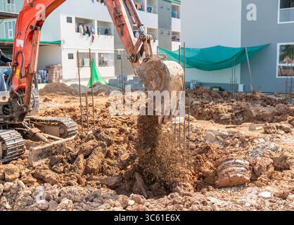 Ein Minibagger füllt den Boden in die Pfahlgrube. Stockfoto