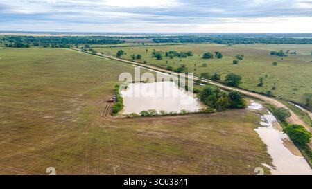 Atemberaubende Aussicht aus der Luft auf eine ruhige Landschaft in Casanare, Kolumbien, mit einem ruhigen Teich umgeben von üppigem Grün und offenen Feldern. Stockfoto