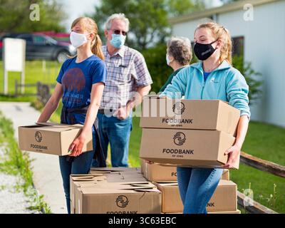 16. Mai 2020, Perry, Iowa, USA: Freiwillige warten auf ein Auto während einer Fahrt durch Foodbank von Iowa in der Crossroads Church in Perry. Die Ernährungsunsicherheit hat in Iowa aufgrund der Pandemie-Abschaltungen in die Höhe getrieben. Die Notkammer in Perry verteilte alle 200 Essensboxen in weniger als 45 Minuten. Der Verbrauch von Notlebensmitteln in der Speisekammer hat sich seit März in Perry mehr als verdoppelt. Die Schweinefleisch verarbeitende Fabrik in Tyson in Perry ist der größte Arbeitgeber der Gemeinde. Es wurde wegen einer Tiefenreinigung abgeschaltet, da viele Arbeiter im Werk positiv auf COVID-19 getestet haben. Seit Beginn des Coronavirus (SARS- Stockfoto