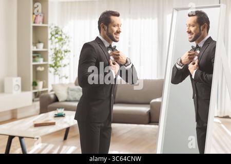 Junger, eleganter Mann, der sich vor einem Spiegel zuhause vorbereitet Stockfoto