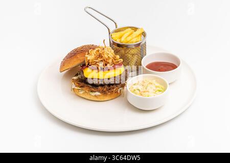 Köstlicher Gourmet-Burger mit Cheddar-Käse, gebratenen Zwiebeln, Krautsalat und Pommes frites Stockfoto
