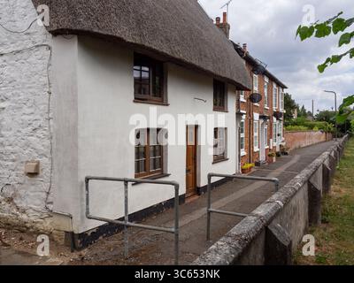 Traditionelles weißes Strohhaus neben dem Kirchhof in Hanslope Village, Buckinghamshire, Großbritannien Stockfoto