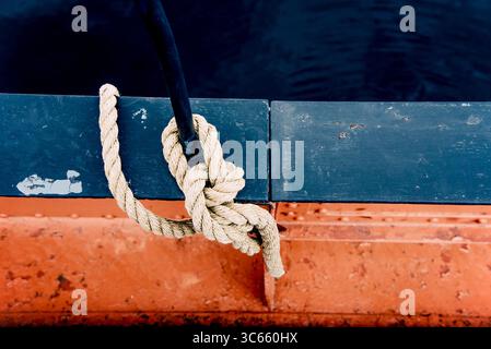 Nahaufnahme eines Festmacherseils mit einem geknüpften Ende, das um die Klammer auf einem Segelboot mit Pier-Ausrüstung gebunden ist Stockfoto