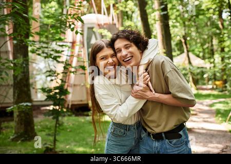 Das Paar lacht und liebt, während es sich in einer ruhigen, baumreichen Umgebung umgibt. Stockfoto