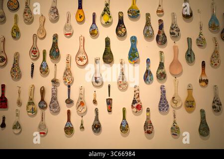 Eine Sammlung von bunten antiken Löffeln aus verschiedenen Ländern, ausgestellt an einer Wand. Stockfoto