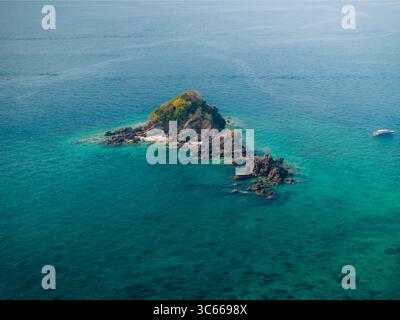 Aus der Vogelperspektive auf eine zerklüftete Insel, umgeben von türkisfarbenem Wasser, steht als einsames Juwel in der weiten Weite des Meeres, Phru Nai, Phang Nga, Thailand. Stockfoto