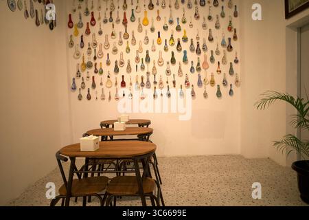 Eine Sammlung von bunten antiken Löffeln aus verschiedenen Ländern, die an einer Wand in einem Raum ausgestellt sind. Stockfoto