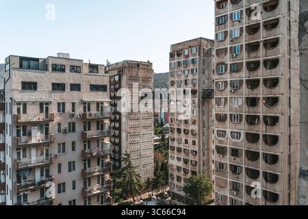 Fotos von alten Wohngebäuden aus Betonplatten aus den 1970er Jahren in Tiflis, Georgien. Diese ikonischen Beispiele brutalistischer Architektur aus der Sowjetzeit spiegeln den krassen, utilitaristischen Stil jener Zeit wider. Rohtexturen, sich wiederholende Geometrien und verwitterte Fassaden sprechen vom historischen und sozialen Kontext der Stadtentwicklung während der Sowjetzeit. Stockfoto