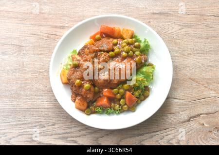 Geschmortes Schweinefleisch in Soße-Eintopf mit frischem Salat auf Teller Stockfoto