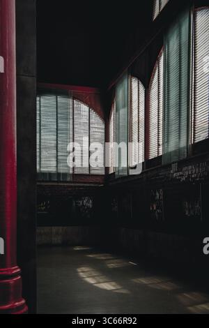 Porto, Portugal - 17. Juni 2022: Blick auf ein schwach beleuchtetes Inneres, mit Sonnenlicht, das durch die Jalousien filtert und ätherische Muster auf den Boden wirft. Stockfoto