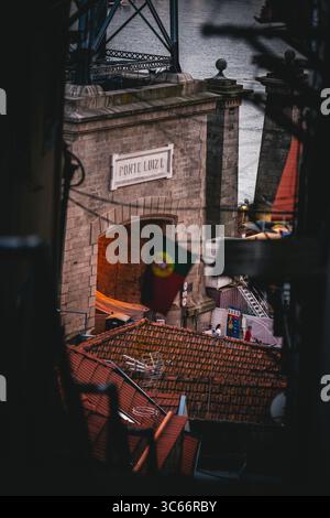 Porto, Portugal - 17. Juni 2022: Blick auf den Bogengang Ponte Luís I, wo die portugiesische Flagge stolz über den Terrakotta-Dächern hängt. Stockfoto