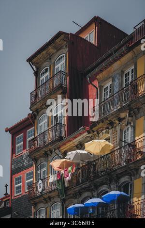 Porto, Portugal - 17. Juni 2022: Blick auf alte Gebäude mit bunten Fassaden und schmiedeeisernen Balkonen, die im Sonnenlicht getaucht sind. Stockfoto