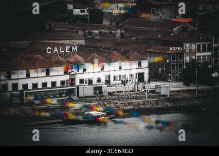 Porto, Portugal - 17. Juni 2022: Blick auf die lebhaften Gebäude Calem und Kopke, die sich auf dem Fluss Douro spiegeln, ein Farbentanz vor den alten Dächern. Stockfoto