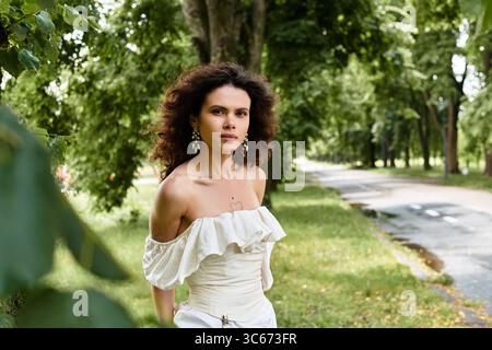 Eine junge Frau in einem weißen Kleid genießt die Ruhe eines grünen Parks. Stockfoto