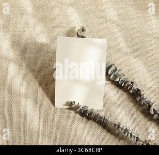 Echt gefertigtes Foto leere weiße Karte getrockneter Eukalyptus hinterlässt Zweige beige Schatten-Overlay-Mockup-Design Stockfoto