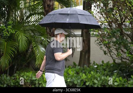24. Mai 2020, Sunny Isles Beach, FL, USA: Ein Mann mit einem Schirm spaziert am Don Soffer Exercise Trail in Aventura am Sonntag, 24. Mai 2020. (Kreditbild: © TNS via ZUMA Wire) Stockfoto
