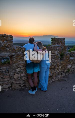 Umarmtes Paar, das die Aussicht bei Sonnenuntergang von den Ruinen des Schlosses, Begur, Spanien, genießt Stockfoto
