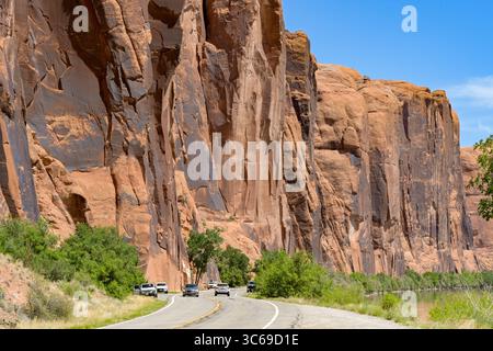 Moab, Utah, USA - 25. Mai 2025: Fahrzeuge, die auf der Potash Road entlang des Colorado River unter riesigen Felsen in der Nähe von Moab fahren Stockfoto