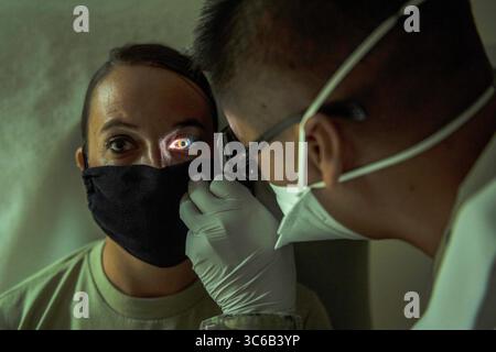 16. Mai 2020 - Andersen AFB, Guam - U.S. Air Force Capt. Everlino Ramos, 36th Medical Operations Squadron, Familienarzt, führt am 16. Mai 2020 eine Augenuntersuchung an einem Patienten durch. Die Andersen Medical Clinic hat ihre Arbeitszeit verlängert, um den Bedürfnissen von Rentnern, die während der Woche keine medizinische Versorgung erhalten können, weiter gerecht zu werden. (Bild: © U.S. Air Force/ZUMA Wire/ZUMAPRESS.com) Stockfoto