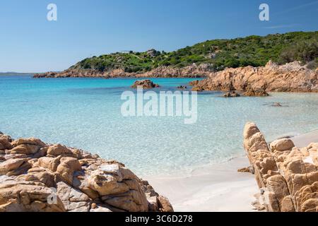 Romazzino, Costa Smeralda, Gallura, Sardinien, Italien. Blick von der Spiaggia del Principe über klares Flachwasser zur bewaldeten felsigen Halbinsel. Stockfoto