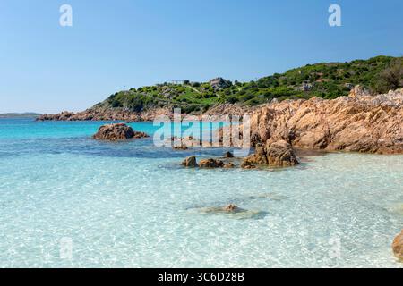 Romazzino, Costa Smeralda, Gallura, Sardinien, Italien. Blick von der Spiaggia del Principe über klares Flachwasser zur bewaldeten felsigen Halbinsel. Stockfoto