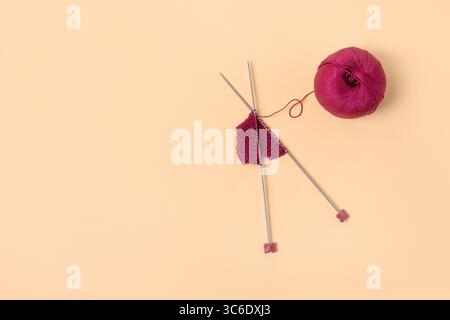 Vinous knitted wool on orange background with knitting needles for knitting warm clothes and hobbies needlework Stockfoto