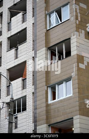 Ein abgenutztes Apartmentgebäude mit kaputten Fenstern und abblätternden Fliesen deutet auf verlorene Leben hin. Stockfoto
