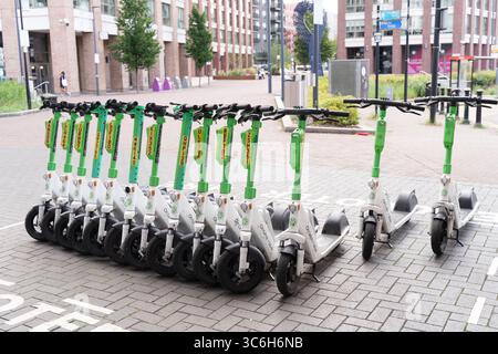 Eine Gruppe von E-Scootern mit Lime-Verleih parkten ordentlich in einer ausgewiesenen Rollerbucht vor dem Eingang zu einer Londoner U-Bahn-Station. UK, Stockfoto