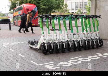 Eine Gruppe von E-Scootern mit Lime-Verleih parkten ordentlich in einer ausgewiesenen Rollerbucht vor dem Eingang zu einer Londoner U-Bahn-Station. UK, Stockfoto
