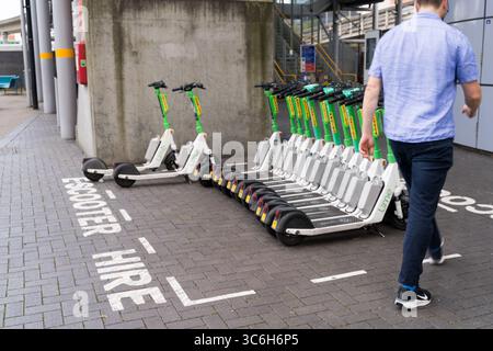 Eine Gruppe von E-Scootern mit Lime-Verleih parkten ordentlich in einer ausgewiesenen Rollerbucht vor dem Eingang zu einer Londoner U-Bahn-Station. UK, Stockfoto