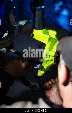 Einbau der Rennscheibenbremse mit leuchtend grünem Achsschenkel an der Aufhängung. Einbau der Vorderradaufhängung und der Bremsscheibe. Einbau der Performance-Federung Stockfoto