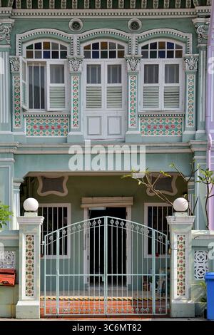 Fassade eines hellgrünen, konservierten Straits Chinese Peranakan Terrassenhauses mit verzierten Rokoko-Putzarbeiten und bunten Mosaikfliesen Stockfoto