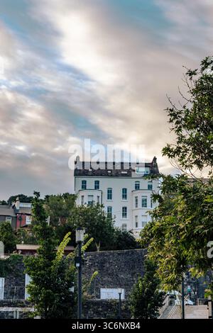 25. Juli 2025 Cork, Irland Eine charmante urbane Szene zeigt lebhaftes Grün und ein historisches Gebäude vor einem dramatischen Himmel Stockfoto