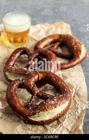 Frisch gebackene hausgemachte weiche Deutschland Salzbrotbrezel mit Salz auf rustikalem Ttisch mit einem Glas Bier. Stockfoto