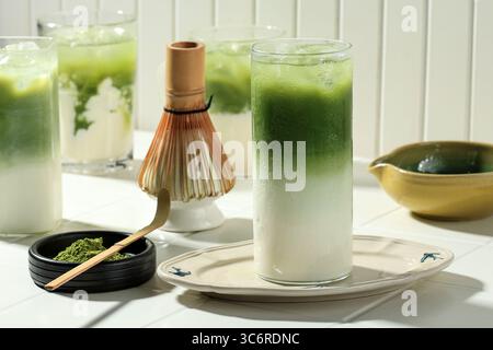 Ein Glas Eismatcha Latte, grüner Tee mit Milch und Sojamilch. Matcha-Tee mit Matcha-Puderlöffel Stockfoto