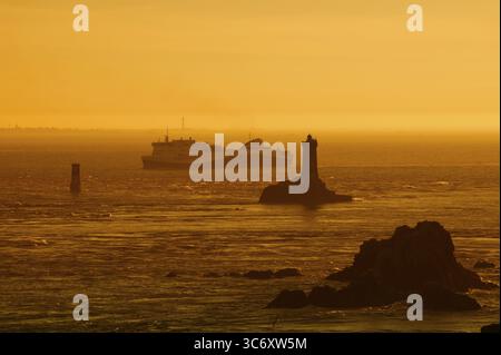 Leuchtturm Phare de la Vieille und Fährschiff bei Sonnenuntergang, Pointe du Raz, Cap Sizun, Département Finistere, Bretagne, Frankreich Stockfoto
