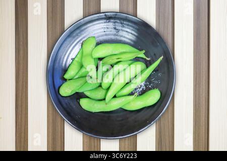 Stanzschnitt von frischen grünen Erbsen auf braunem farbigem Holzstreifenhintergrund. Stockfoto