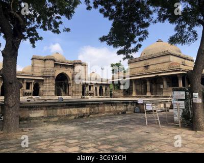 Ein alter Innenhof einer Moschee unter einem klaren Himmel mit Bäumen im Hintergrund und Steinboden, Bai Harir Moschee, Ahmedabad, Gujarat, Indien Stockfoto