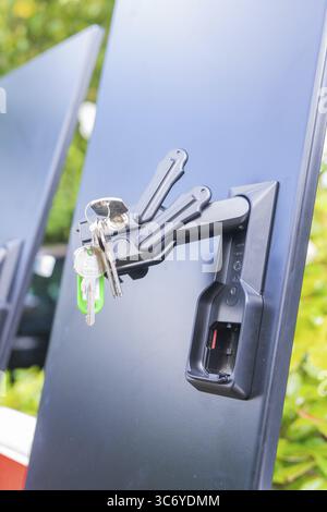 Ein paar Schlüssel hängen an einem Schloss auf schwarzem Hintergrund in Nahaufnahme, Installation einer Ladestation für Elektroautos, Calw, Deutschland Stockfoto