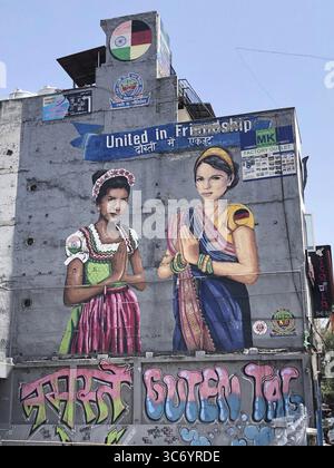 Wandgemälde von zwei Frauen in traditioneller Kleidung, einer Indianerin in einem bayerischen Dirndl, einer Deutschen in einem Sari, Neu-Delhi, Indien Stockfoto