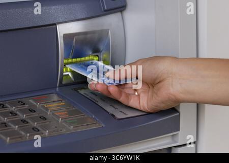 Weibliche Hand, die die Kreditkarte in den Geldautomat-Steckplatz einführt. Bankwesen und Sicherheit. Das Foto wurde in Kiew, Ukraine, aufgenommen Stockfoto