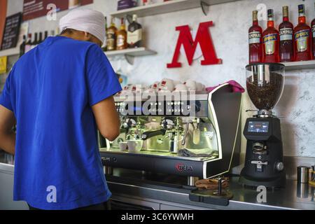 Ein Barista arbeitet am 25. Juli 2025 in einem Café in Cremona, Italien, mit einer Espressomaschine und Kaffeetassen Stockfoto