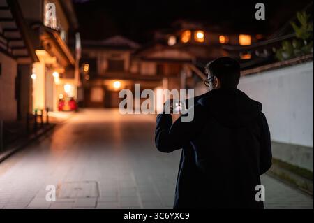 Mann, der nachts in der traditionellen japanischen Straße fotografiert Stockfoto