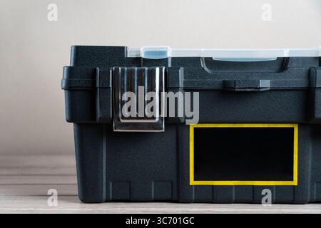 Nahaufnahme eines schwarzen Kunststoff-Werkzeugkastens mit Metallverriegelung und transparentem Deckel. Der Werkzeugkasten hat einen gelb umrandeten Beschriftungsbereich auf der Vorderseite Stockfoto