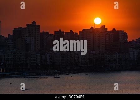 Feuriger orangefarbener Sonnenuntergang über der wunderschönen Stadt Alexandria, Ägypten Stockfoto