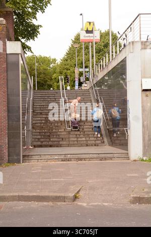 Eine junge Frau hilft einem älteren Mann mit seinem Warenkorb auf der Treppe am U-Bahnhof Coolhaven, Rotterdam, Niederlande Stockfoto