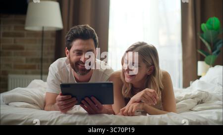Lachende kaukasische Familie verheiratetes Paar mit Tablet im Schlafzimmer Liebe fröhlich Freund Freundin Tippgerät Frau Kauf Waren App Stockfoto